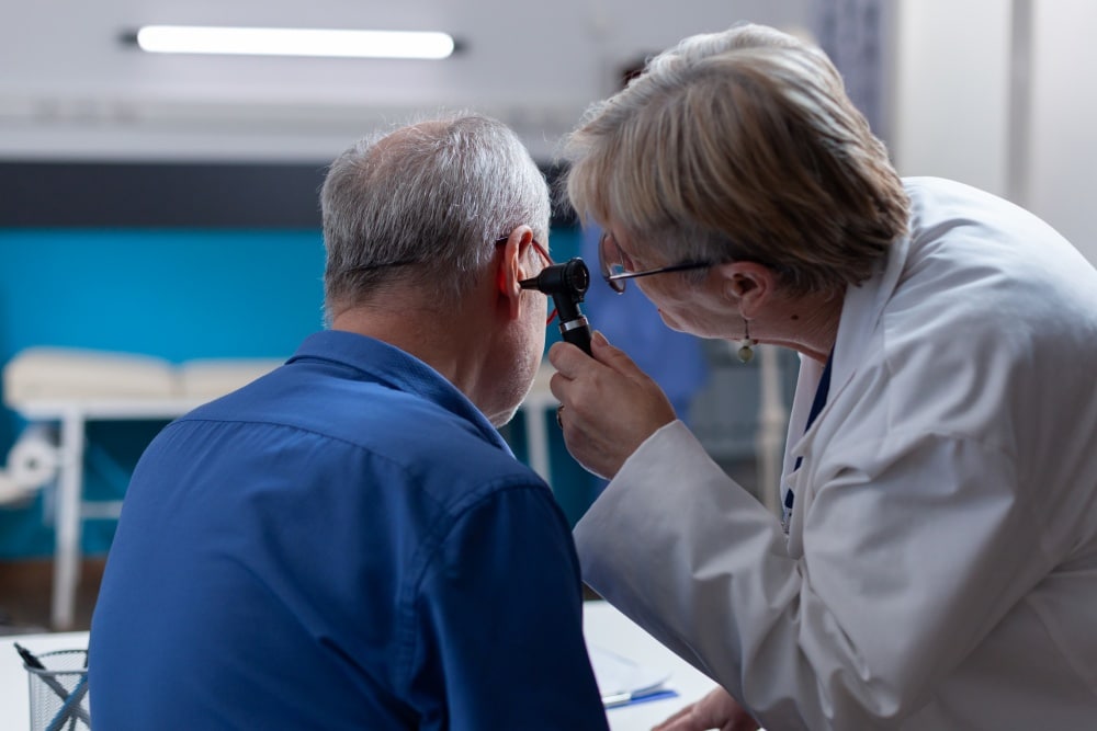 Physician holding otoscope to do ear consultation for patient at checkup visit